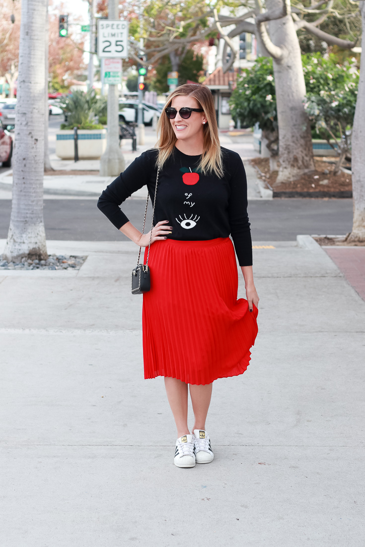 The Fashionista Momma styles a graphic sweater and pleated skirt.