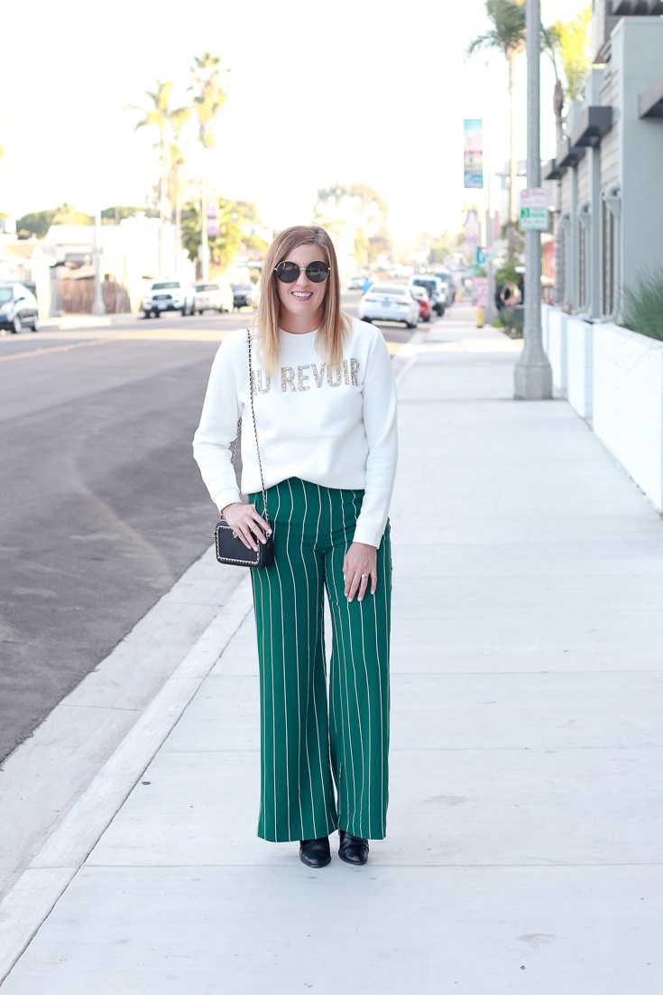 The Fashionista Momma shares wide leg pants and a graphic sweatshirt.