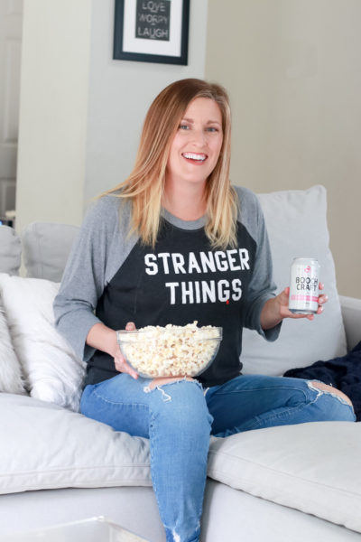 Binge Worthy Shows featured by popular mom lifestyle blogger, The Fashionista Momma; woman watching TV with popcorn and Boochcraft.